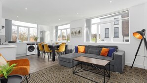 Ein modernes Wohnzimmer mit einem grauen Sofa, einem Couchtisch und einem gemusterten Teppich.