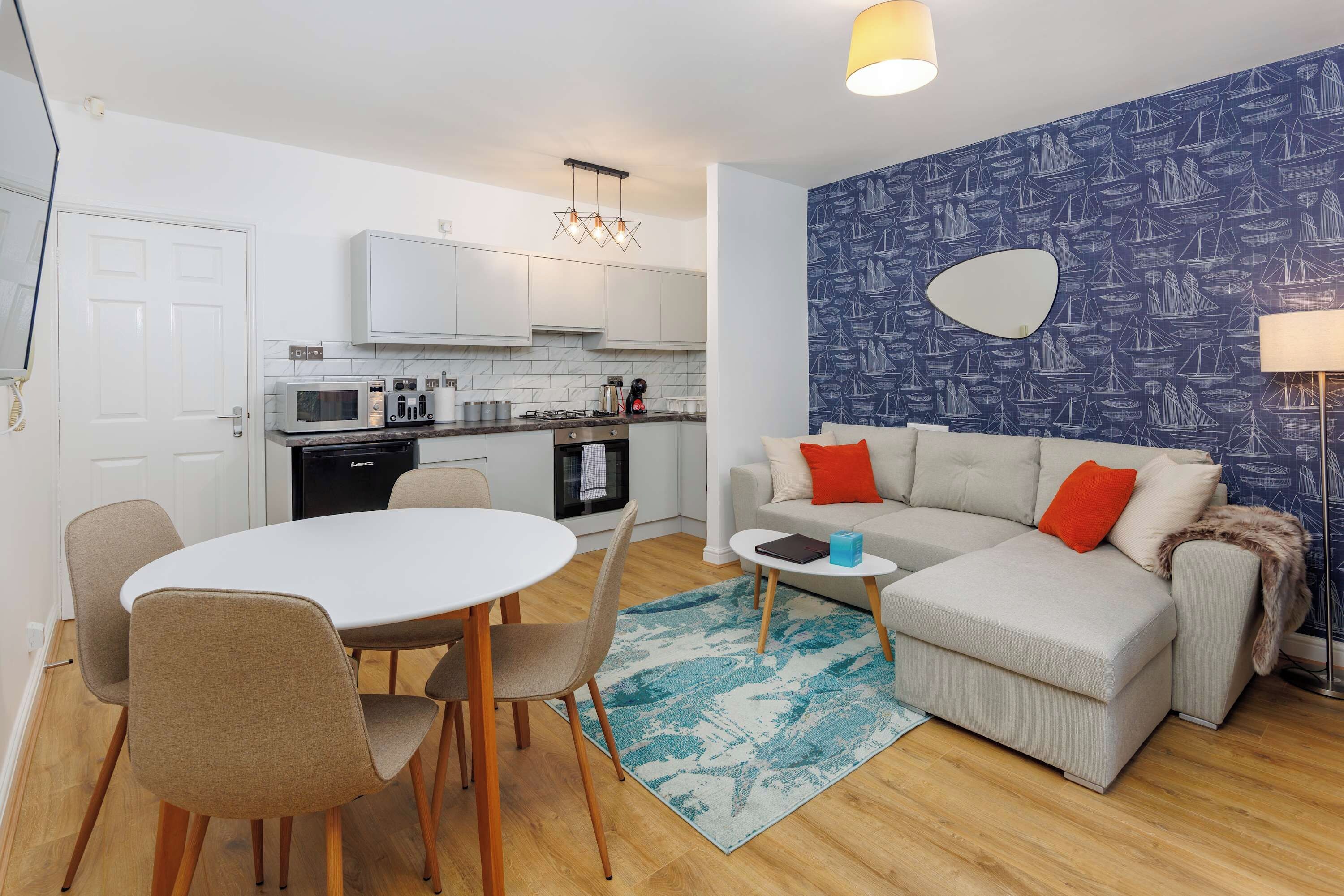 A compact living space with a kitchenette, a dining area, and a seating area with a sofa and chairs.