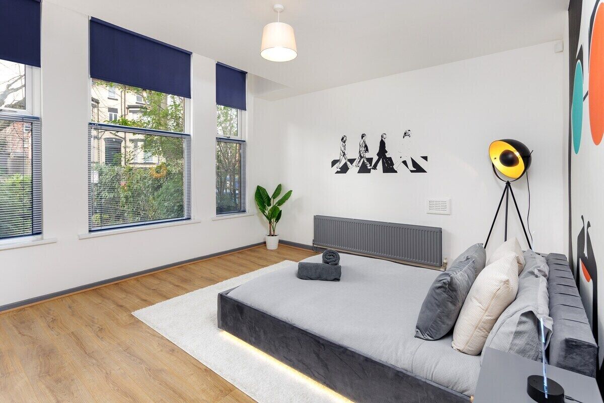 A modern bedroom with a bed, a radiator, a potted plant, and a wall art piece.