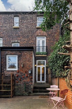 A brick building with a small front porch, a wooden ladder, and a table with chairs outside. - Flatzy - Iconic Beatles and Liverpool Culture Home (Liverpool)