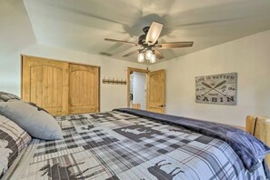 A bedroom with a bed, a ceiling fan, wooden doors, and a wall sign.