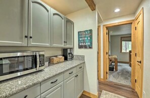 A kitchen with a microwave, cabinets, and a coffee maker on the counter.
