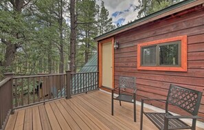 A wooden cabin with a deck, a door, and a window.