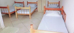Una habitación con cuatro camas de madera dispuestas en fila, cada una con un colchón blanco y una almohada.