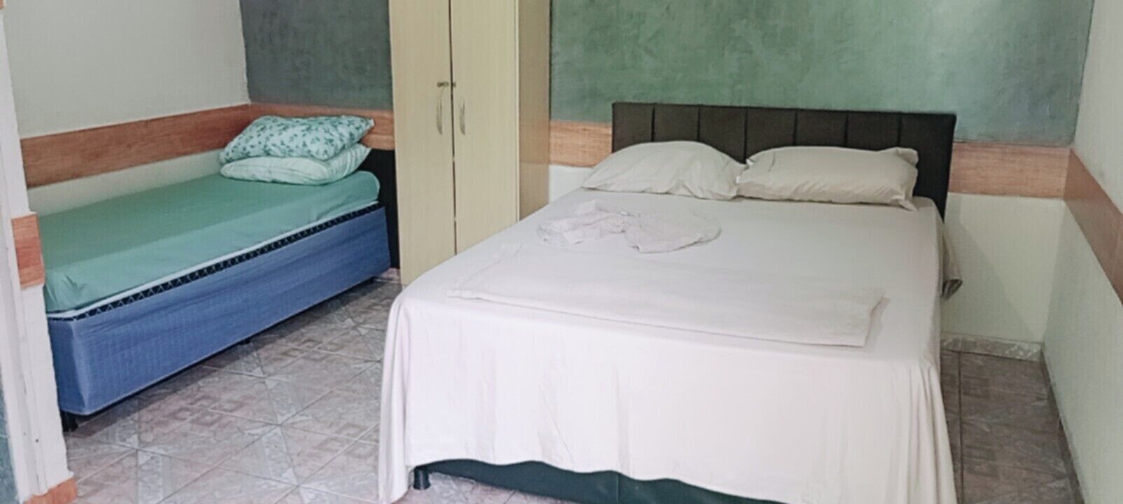 A bedroom with a bed, a wardrobe, and a small bench.