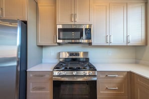 A kitchen with stainless steel appliances, including a microwave and stove, and light-colored cabinetry.