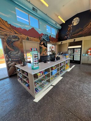 A children's play area with a counter, shelves with toys, and a mural of animals on the wall.