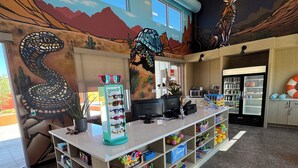 A children's play area with a counter, shelves with toys, and a mural with a snake and a turtle.
