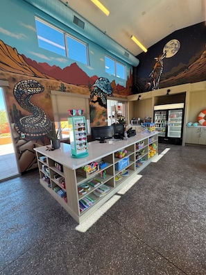 A children's play area with a counter, shelves with toys, and a mural with a snake and a turtle.
