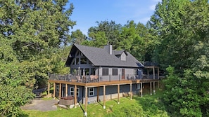 Ein zweigeschossiges Haus mit einer Terrasse, umgeben von Bäumen.