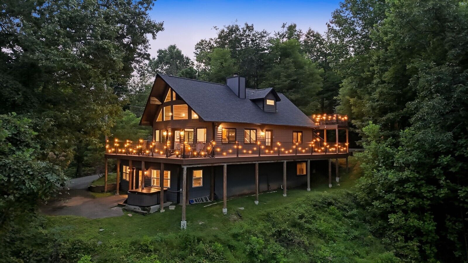 Une maison en bois à deux étages, dotée d’un balcon et entourée d’une végétation luxuriante.