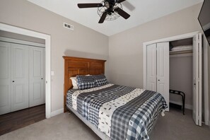 Ein Schlafzimmer mit Bett, Deckenventilator, Kleiderschrank und Tür.