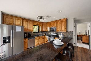 A modern kitchen with wooden cabinets, stainless steel appliances, and a granite countertop. - King of Mountain: Hot Tub, Grill, Games, Pet-Friendly! (Gatlinburg)