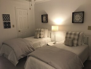 Ein Schlafzimmer mit zwei Betten, einem Nachttisch, einer Lampe und Wanddekoration.