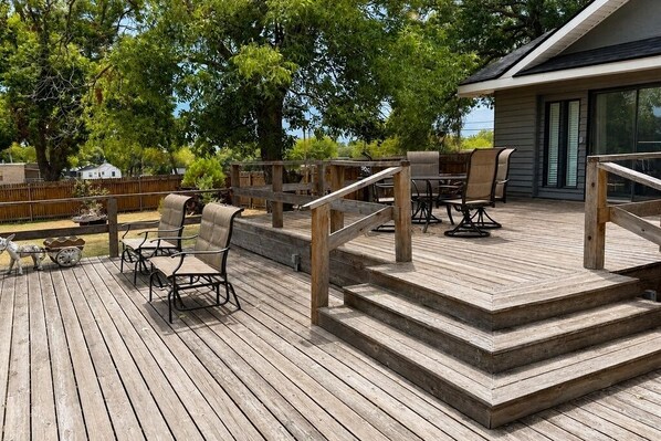 A wooden deck with outdoor seating and a staircase leading to a building.