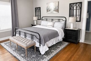 A bedroom with a bed, bedside tables, a bench, and a rug.