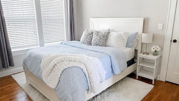Une chambre à coucher avec un lit, une table de chevet, une lampe et une fenêtre avec des stores.