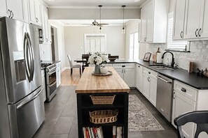 Una cocina moderna con electrodomésticos de acero inoxidable, una isla de madera y armarios blancos.