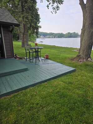 A deck with outdoor furniture overlooking a lake.