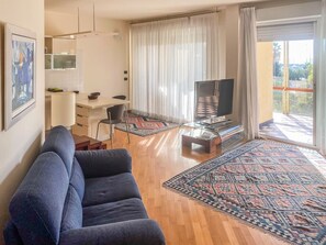 A living room with a sofa, a coffee table, a TV, and a large window with curtains. - Mediterranean - Sanremo (Sanremo)