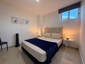 Une chambre à coucher avec un lit, des tables de chevet, une chaise et une fenêtre.