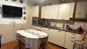 A compact kitchen with a dining table, a microwave, and a gas stove.
