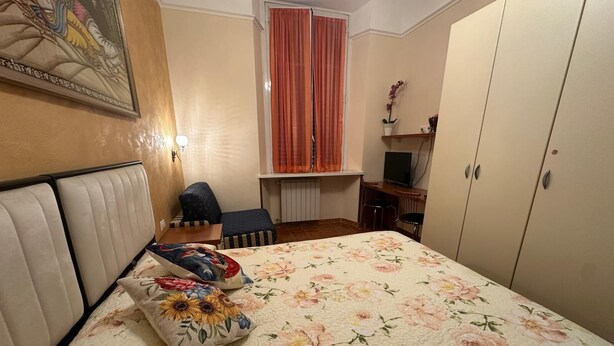 A bedroom with a bed, a desk, a chair, and a wardrobe.