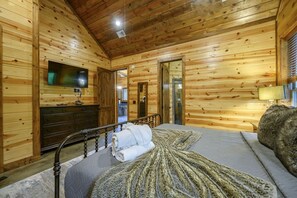 A wooden-paneled room with a bed, a dresser, a television, and a lamp.