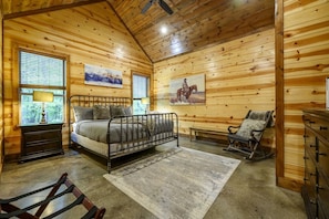 Une chambre à coucher dans une cabane en bois, avec un lit, un fauteuil à bascule, un banc et une commode.