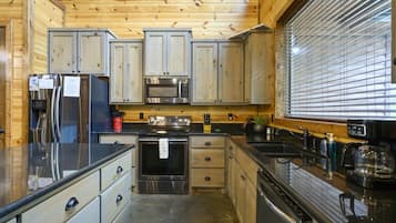 Een keuken met houten kastjes, roestvrijstalen apparatuur en een raam met jaloezieën.