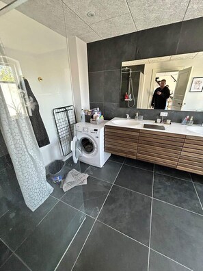 Ein modernes Badezimmer mit Waschmaschine, großem Spiegel und Waschtisch.