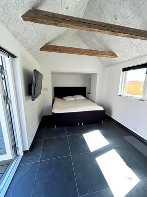 Ein Schlafzimmer mit einem Bett, einem Fernseher und einem Fenster.