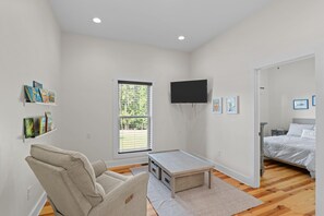 A modern bedroom with a bed, a TV, a bookshelf, and a window. - Lakefront MASTERS WEEK Rental (McCormick)
