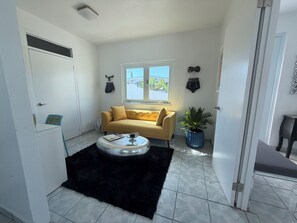 Un espace de vie compact comprenant un canapé, une petite table, une plante en pot et une fenêtre donnant sur un beau paysage.