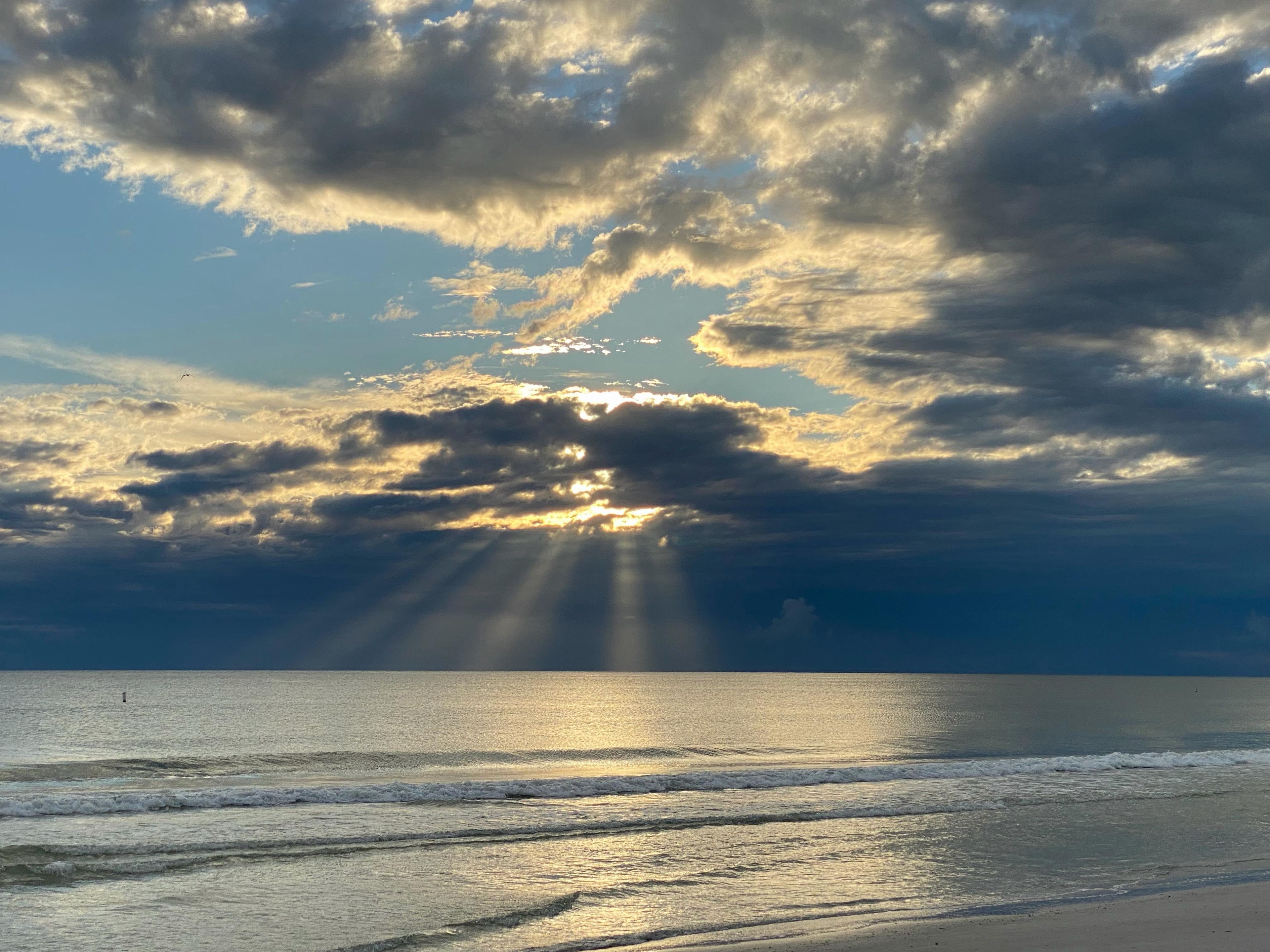 A beach with waves and a cloudy sky.