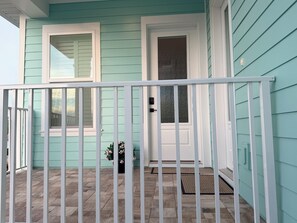 A house with a porch, a door, and a window. - Serene & Luxurious Beach Studio, Heated Pool, Garage & Steps to Sand (St. Pete Beach)