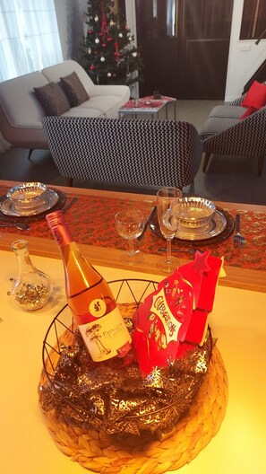 A festive table setting with a bottle, glasses, and a wrapped gift in a decorative bowl. - Villa océan-Achard-Labenne, near the dune.Pool/Spa /Sleeps 8/10 and pets welcome (Labenne)