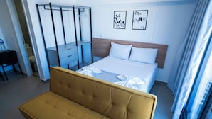 Habitación de hotel con cama, sofá, escritorio y armario.