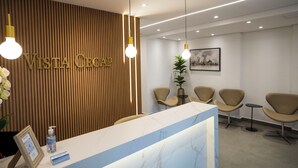 A reception area with a wooden panel wall, a reception desk, and several chairs. - Vista Cecap (Guarulhos)