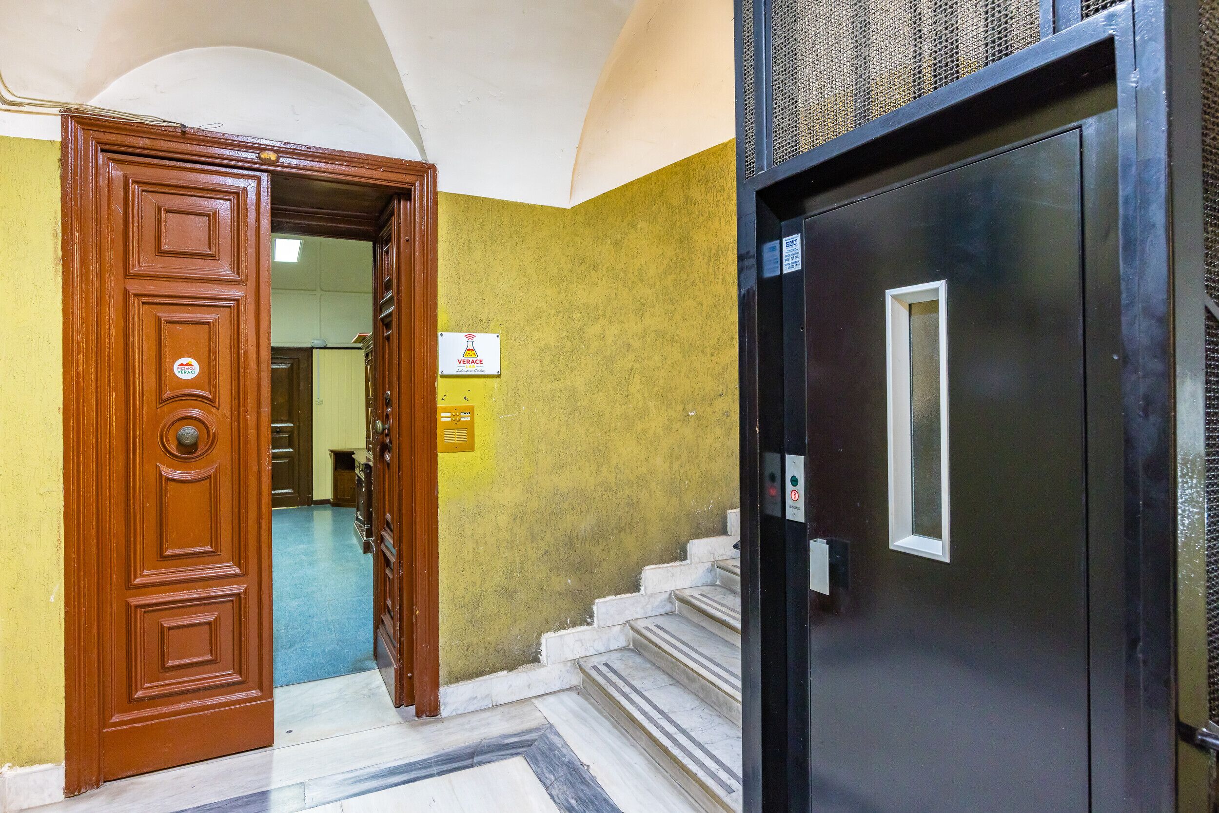 A hotel entrance with a wooden door and a black elevator door.