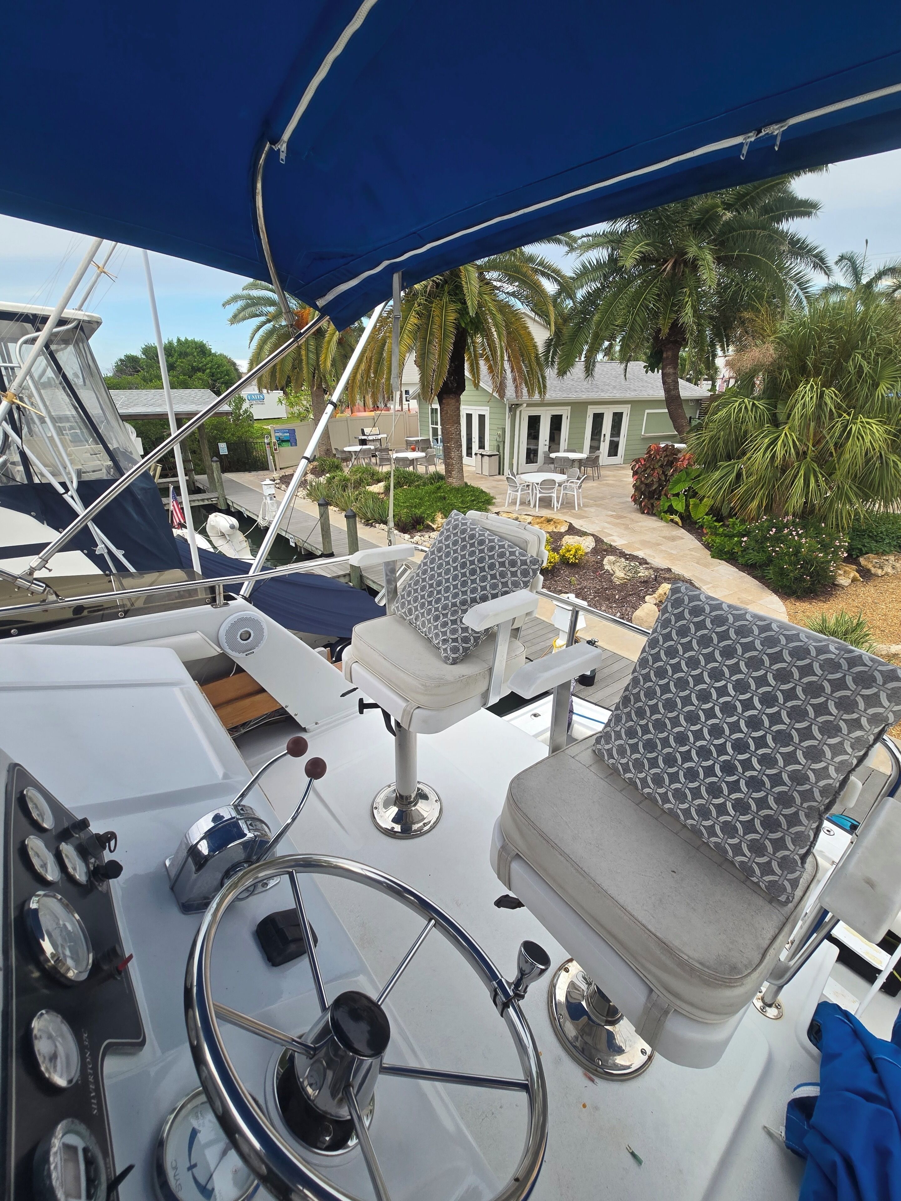 A boat's deck with a steering wheel, control panel, and seating area.