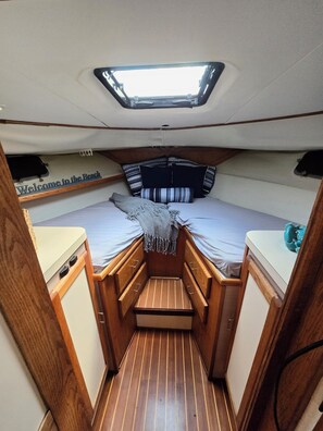 A compact cabin with a bunk bed, a small kitchenette, and a skylight.