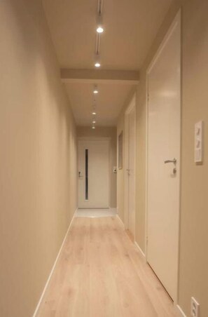 A narrow hallway with wooden flooring and doors on both sides. - Comfortable and elegant apartment (Troms)