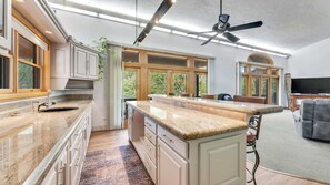 Une cuisine moderne dotée d’un grand îlot central, de meubles en bois et d’un ventilateur de plafond.