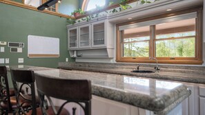 A kitchen with a granite countertop, white cabinets, a window with a view, and a bar area with two chairs. - Waterview w Dock and Fishing, Wrap around deck (Mapleton)