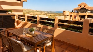 Eine Terrasse mit Tisch und Stühlen, die einen schönen Ausblick auf eine Landschaft mit Gebäuden in der Ferne bietet.