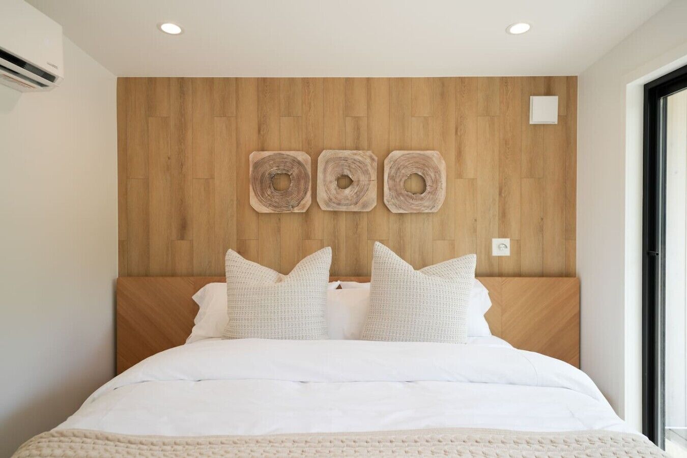 Ein Schlafzimmer mit einem hölzernen Kopfteil, einem Bett mit weißer Bettwäsche und drei runden Wandbildern.