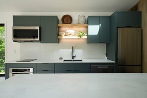 A modern kitchen with a built-in microwave, a stainless steel refrigerator, and a dishwasher. - Modern Scandi Home on a Private Estate (Harbor Springs)