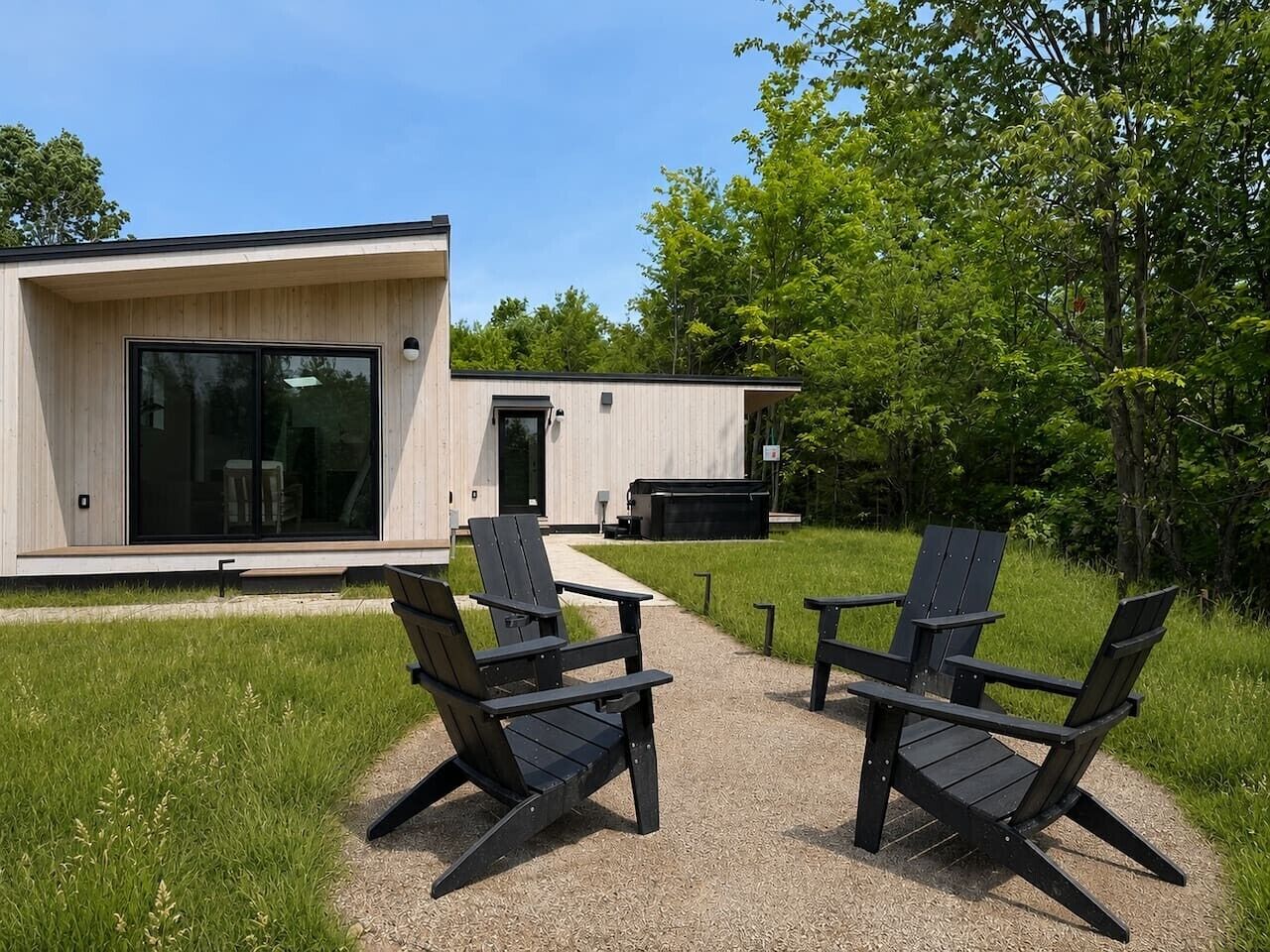 A modern building with a glass door and a patio area with two Adirondack chairs.