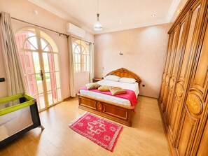 A bedroom with a wooden bed, a red patterned rug, and a wardrobe. - Villa Al Jaouhara - Private Pool, 1-hectare Garden, and Accommodations for 20 Guests (Essaouira)